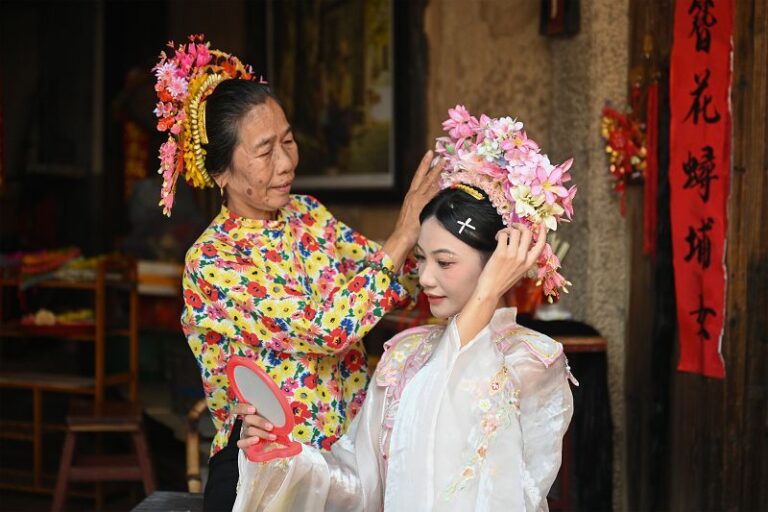 在福建泉州蟳埔村，翁秀珍為遊客「簪花圍」（8月27日攝）。