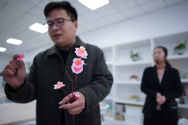 2024年12月20日，天津市武清區絹花展覽館，工作人員向參觀者介紹絹花發展。（資料圖）