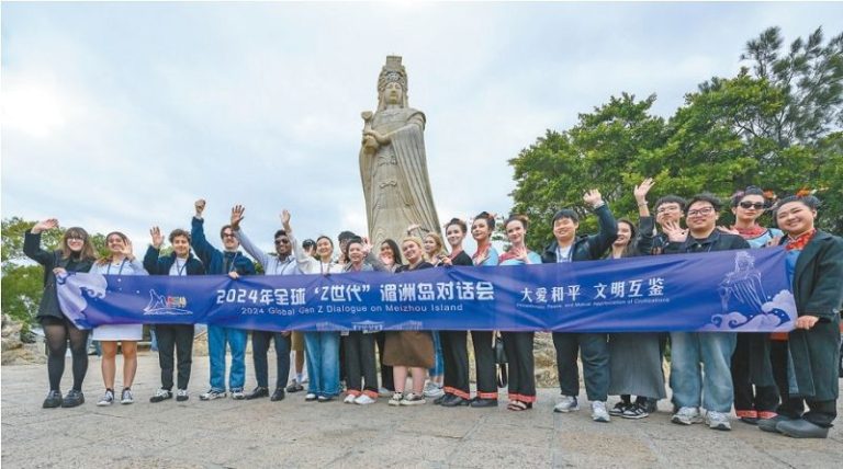 ▲2024年全球「Z世代」湄洲島對話會期間，多個國家和地區的青年在湄洲媽祖祖廟的媽祖石雕像前合影。全媒體記者 蔡昊 攝