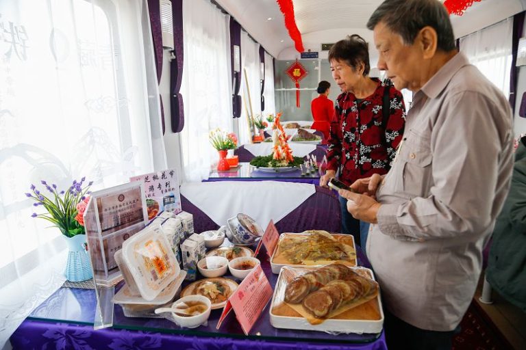 來自新加坡的旅客在餐車內瞭解美食。 中新社