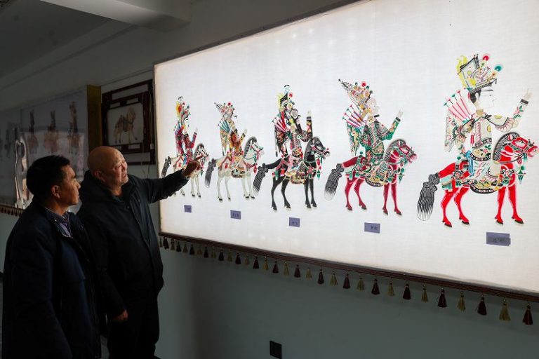 1月20日，青海湟中，王義元（右）介紹皮影製作過程。