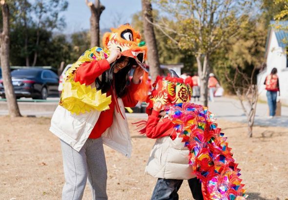 2月18日，蘇州市吳中區旺山，兩岸婚姻家庭的母子一起戴著舞獅道具嬉戲。 中新社