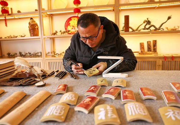 三明市級非遺留青竹刻手藝人曹永生 正在雕刻新春福字作品。