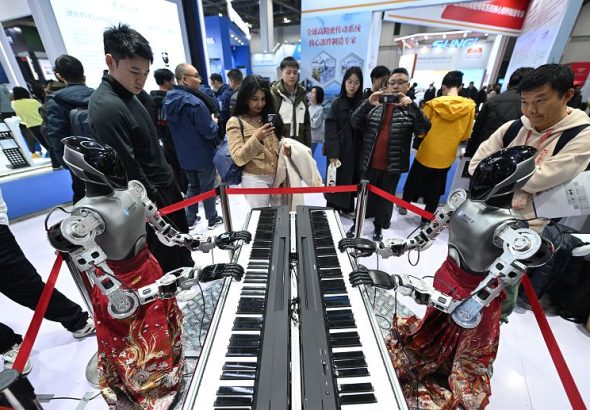 圖為彈鋼琴的人形機器人吸引參觀者。 中新社