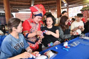 4月17日，李宜霏（左三）在活動上向織娘學習壯錦製作技藝。中新社