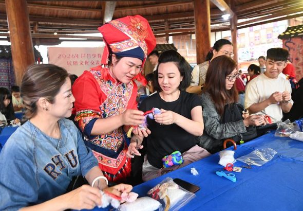 4月17日，李宜霏（左三）在活動上向織娘學習壯錦製作技藝。中新社
