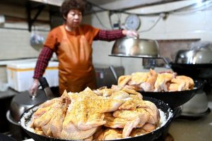 圖為塗抹好秘製醬料的雞放在鋪有粗鹽的鍋內。