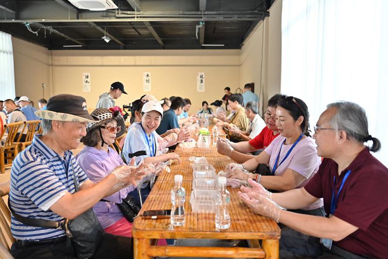 6月26日，兩岸客家鄉親同遊位於廣東河源的客家古村落南園古村，共同製作、品嚐客家美食油果。圖為兩岸客家鄉親製作客家美食。 中新社