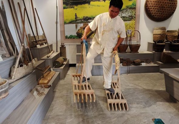 聯合梯田農耕文化博物館館長廖燕楚在館內向遊客展示梯田傳統農具的使用方法。