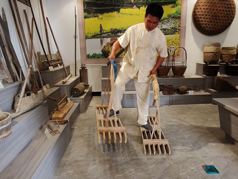聯合梯田農耕文化博物館館長廖燕楚在館內向遊客展示梯田傳統農具的使用方法。