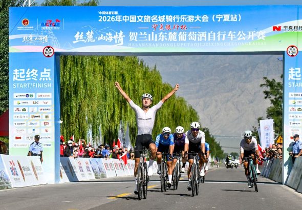 圖片2.男子公路精英組參賽選手張坤率先衝過終點線，高舉雙臂慶祝奪冠。