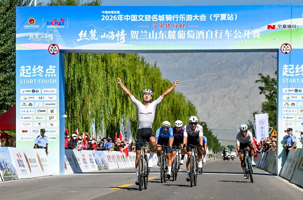 圖片2.男子公路精英組參賽選手張坤率先衝過終點線，高舉雙臂慶祝奪冠。