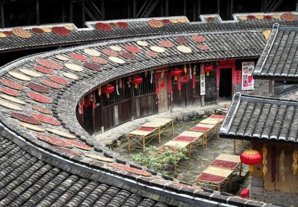 福建土樓永定初溪土樓群核心的集慶樓，數百個竹簸箕沿著環形迴廊整齊鋪開，金黃的稻穀、紅彤彤的辣椒、飽滿的玉米、橙紅的柿子錯落擺放。