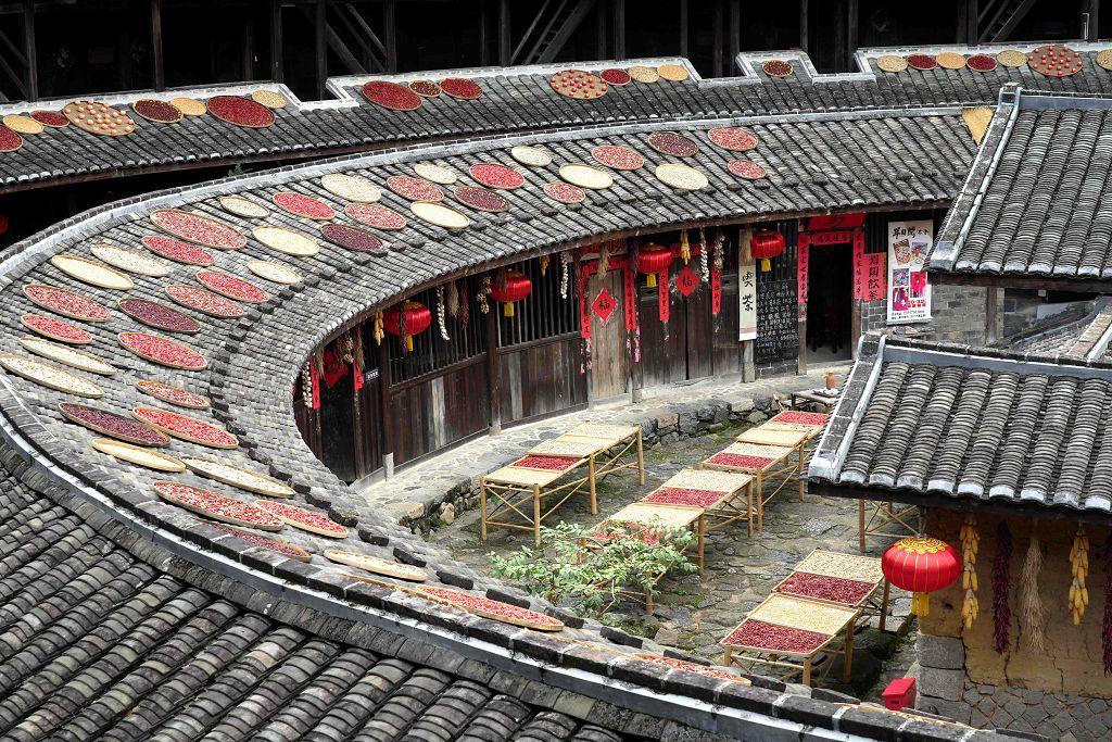 福建土樓永定初溪土樓群核心的集慶樓，數百個竹簸箕沿著環形迴廊整齊鋪開，金黃的稻穀、紅彤彤的辣椒、飽滿的玉米、橙紅的柿子錯落擺放。
